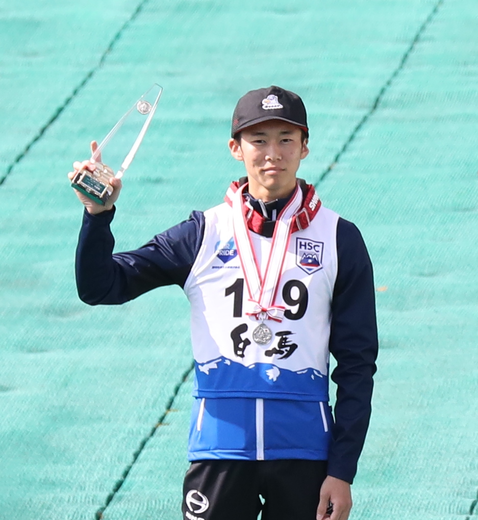 写真:入賞トロフィーを右手に掴み、首からメダルを下げ、喜びの笑みを浮かべる山本選手